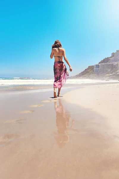 Deixando sua marca no verão. Foto retrovisor de uma jovem mulher sexy andando na praia. — Fotografia de Stock