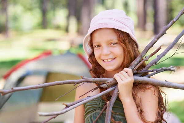 Twigs for our marshmallow smores. Shot of a young girl holding twigs in front of her campsite. — Stock Photo, Image