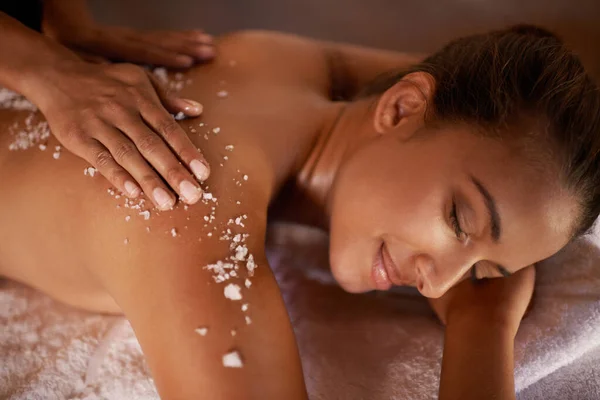 Não há nada mais relaxante do que isto... Tiro de uma jovem mulher desfrutando de um tratamento de esfoliação de sal em um spa. — Fotografia de Stock