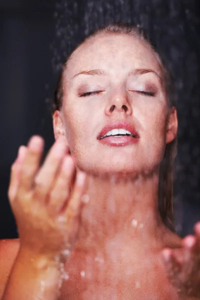 Csinos kaukázusi nő fürdik a zuhany alatt. Higiénia - Closeup egy csinos kaukázusi nő zuhany alatt, sötét háttér. — Stock Fotó