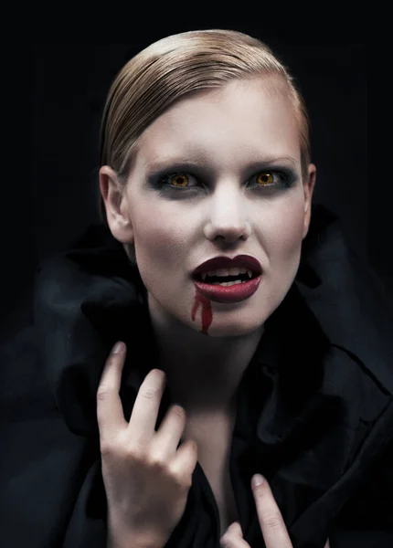 Napędzany chęcią pożywienia się. Prowokacyjna wampirzyca z krwią spływającą po brodzie na ciemne tło.. — Zdjęcie stockowe