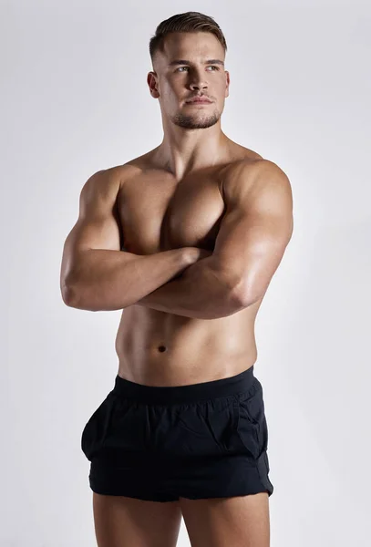 Prende sul serio il fitness e si vede. Girato di un giovane muscoloso in posa su uno sfondo bianco. — Foto Stock