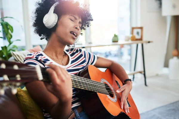 A música é uma chupeta natural. Tiro de uma mulher usando fones de ouvido enquanto tocava guitarra em casa. — Fotografia de Stock