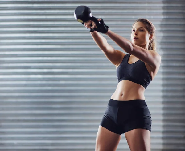 A dar-lhe tudo o que tinha. Tiro de uma jovem mulher trabalhando com kettlebells. — Fotografia de Stock