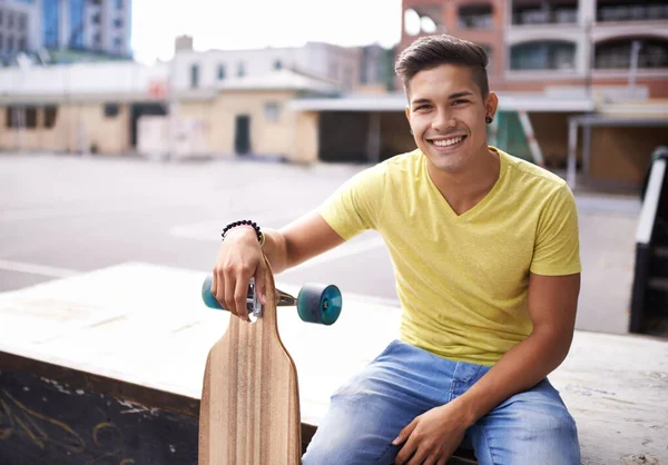 C'est comme ça que je roule. Portrait d'un jeune homme assis avec son skateboard dans la ville. — Photo