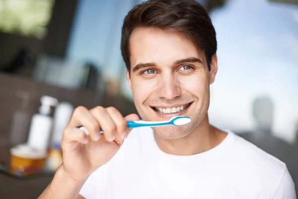 Убедиться, что его улыбка сверкает. Крупный план молодого человека, чистящего зубы. — стоковое фото