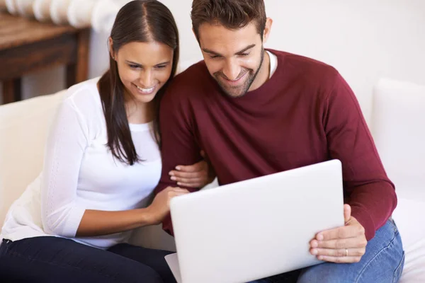 In love online. An affectionate young couple using their laptop together at home. — Stock Photo, Image