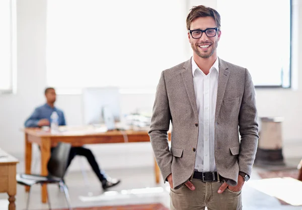 Je zult dit kantoor geweldig vinden. Portret van een jongeman in een kantoor met een collega op de achtergrond. — Stockfoto