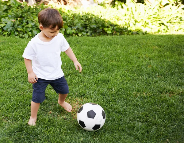 Voetbal in de tuin. Een lief jongetje met een voetbal in de achtertuin. — Stockfoto