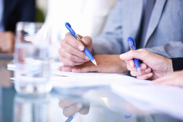 Firmando en la línea de puntos. Vista recortada de un grupo de empresarios que trabajan en una mesa sobre algunos documentos. Fotos de stock