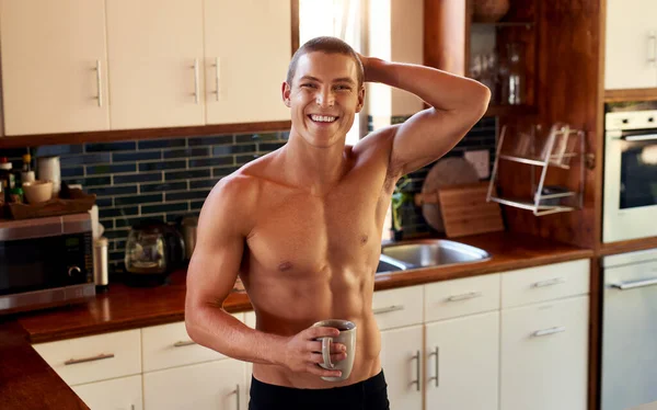 Café no conforto da minha casa. Retrato de um belo jovem sem camisa bebendo uma xícara de café na cozinha em casa. — Fotografia de Stock