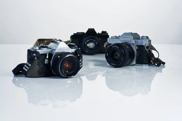 Trio van beeldmakers. Studio shot van verschillende camera 's en hun accessoires. — Stockfoto