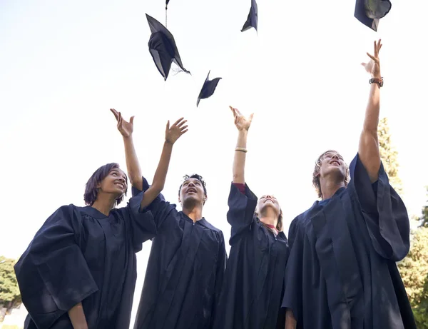O nosso trabalho duro valeu a pena. Um grupo de graduados universitários jogando seus chapéus em celebração. — Fotografia de Stock