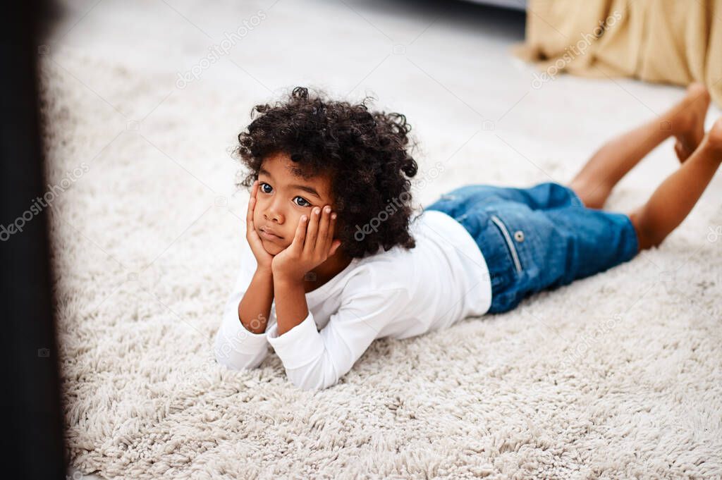 This movie is getting more interesting by the minute. Cropped shot of an adorable little boy lying down on a carpet and watching tv at home.