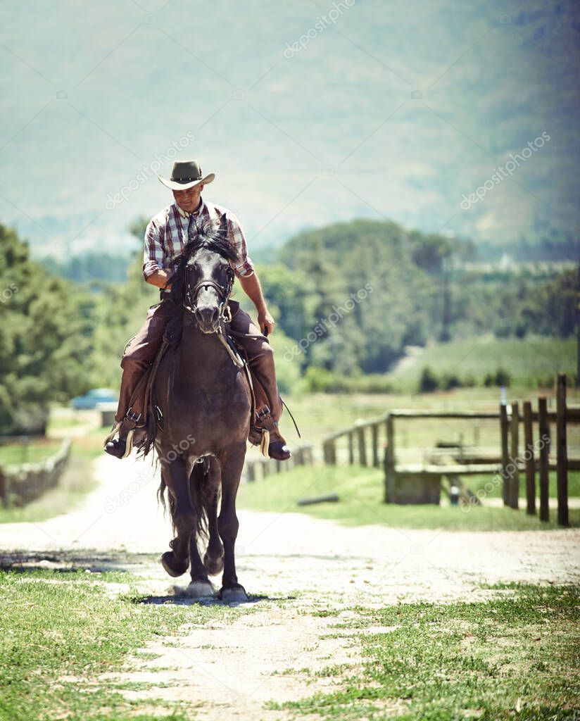 Yeeha. Shot of a cowboy riding his horse on a country lane.