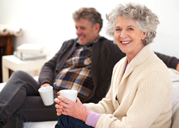 Šťastní doma ve společnosti ostatních. Portrét seniorského páru relaxujícího ve svém obývacím pokoji s kávou. — Stock fotografie