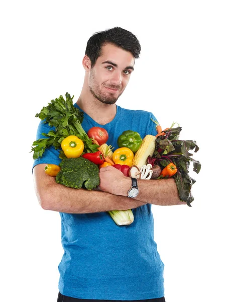 Tengo il buon cibo vicino. Studio ritratto di un bel giovane in posa con una varietà di verdure fresche su uno sfondo bianco. — Foto Stock