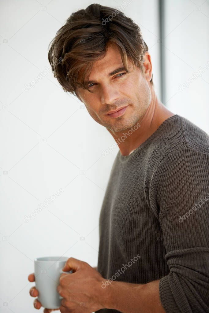 Ready to start the day. A handsome young man standing at home and holding a cup of coffee.