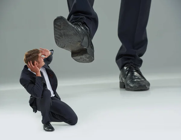 Его растоптал Человек. Обрезанный вид бизнесмена, приседающего, когда гигантский ботинок спускается на него. — стоковое фото