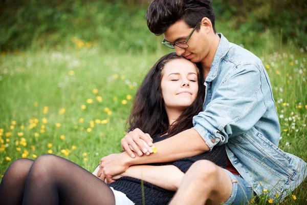 Partager un doux lien. Jeune couple assis ensemble affectueusement dans un champ de printemps. — Photo