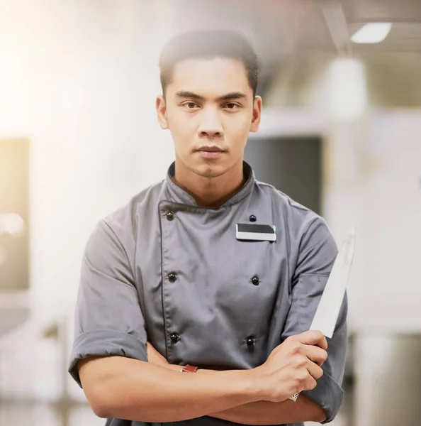 Confiança na cozinha. Retrato recortado de um jovem chef de pé com uma faca em sua cozinha. — Fotografia de Stock