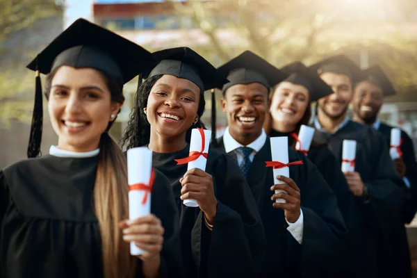 Naše budoucnost je bezpečná. Portrét skupiny mladých studentů držících diplomy v den promoce. — Stock fotografie