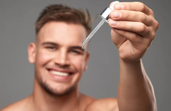 Its not magic, its my skincare secret. Studio shot of a handsome young man applying serum to his face against a grey background. — Stock Photo, Image