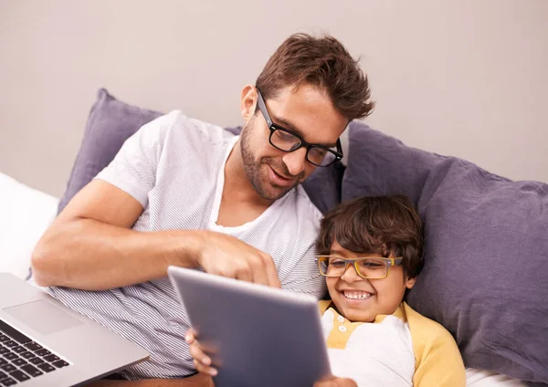 To moja ulubiona. Ojciec i syn leżący na łóżku podczas korzystania z laptopa i tabletu cyfrowego. — Zdjęcie stockowe