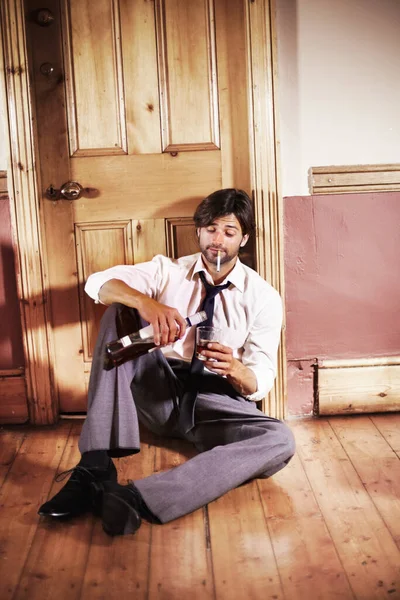 Tal vez sólo uno más..... Borracho joven ejecutivo de negocios sentado en una puerta sirviendo un trago. — Foto de Stock
