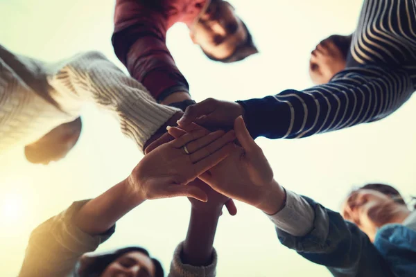 Os verdadeiros amigos mantêm-se juntos. Foto de baixo ângulo de um grupo de estudantes unindo as mãos em solidariedade. — Fotografia de Stock