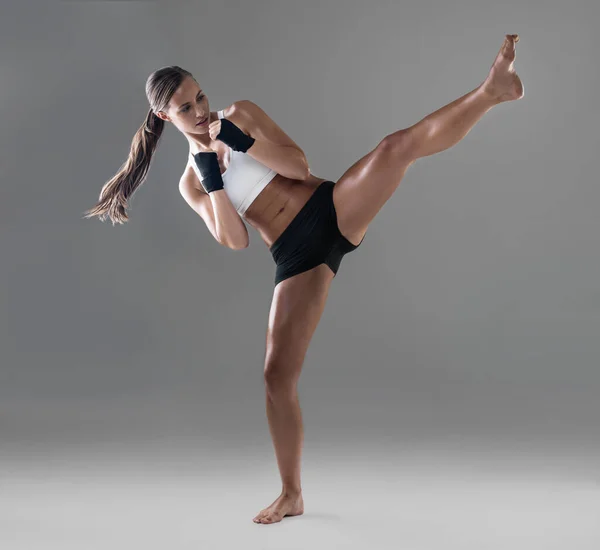 Een tandje hoger schoppen. full length shot van een atletische jonge vrouw oefenen haar kickboxing techniek. — Stockfoto