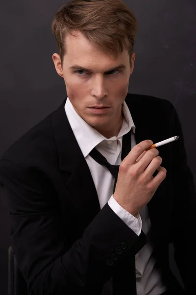 Canalizando James Bond. Un joven guapo con un traje y un cigarrillo en la mano. —  Fotos de Stock