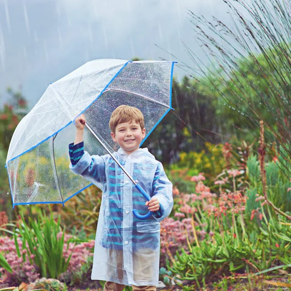 I love the rain almost as much as my garden does. Cropped portrait of a young boy standing outside in the rain. — Stock Photo, Image