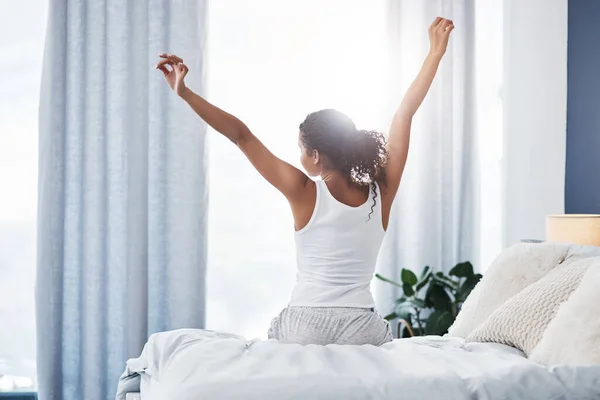 Het is een goede morgen voor mij. Rearview shot van een onherkenbare jonge vrouw stretching terwijl zitten op haar bed in de ochtend. — Stockfoto