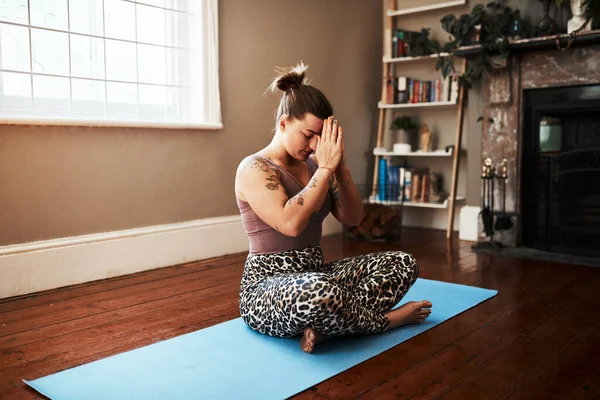 Vähentää stressiä ja hallita ahdistusta meditoimalla. Ammuttu nuori nainen meditoi joogamatolla kotona. — kuvapankkivalokuva