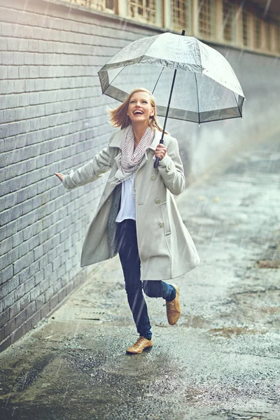 Regnet störde henne ändå aldrig. Full längd skott av en attraktiv ung kvinna som leker i regnet. — Stockfoto