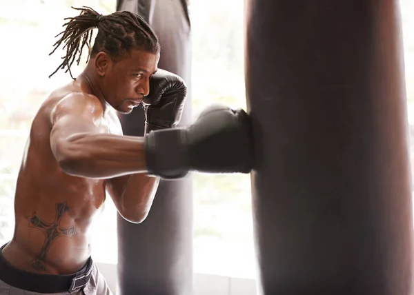Brute kracht. Shot van een jonge bokser oefenen op een bokszak in een sportschool. — Stockfoto