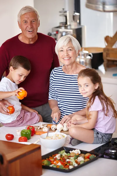 Dinner will be ready in no time. Portrait of a grandparents preparing a meal with their grandchildren. — Stock Photo, Image