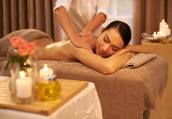 Indulging her senses at the spa. A beautiful young woman enjoying a massage at the spa. — Stock Photo, Image