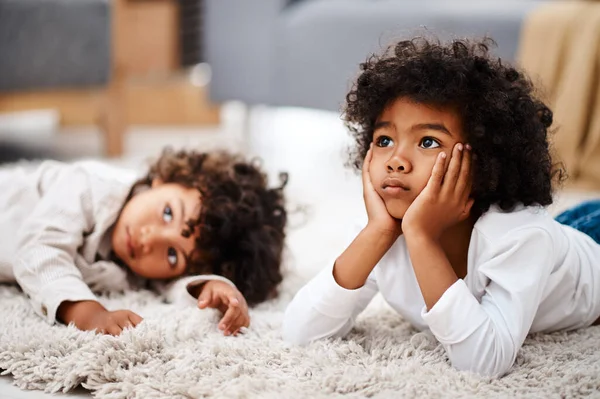 Nous ne pouvons pas garder nos yeux hors de l'écran. Coupé plan de deux adorables petits garçons couchés sur un tapis et regarder la télévision ensemble à la maison. — Photo