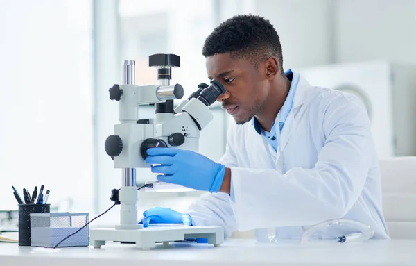 Was für ein interessanter Fund. Schnappschuss eines fokussierten jungen männlichen Wissenschaftlers, der Testproben tagsüber durch ein Mikroskop in einem Labor betrachtet. — Stockfoto