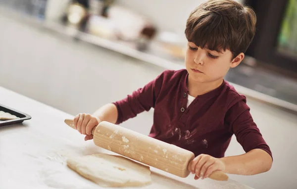 Je to rozený pekař. Postřelen mladého chlapce valící se těsto v kuchyni. — Stock fotografie