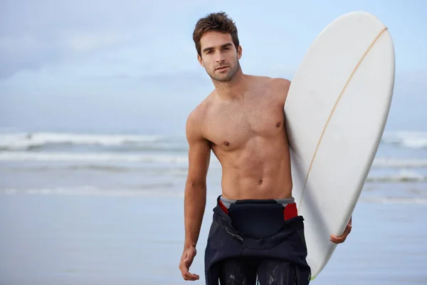 Perseguir ondas é a sua paixão. Um belo jovem surfista na praia desejando uma boa onda. — Fotografia de Stock
