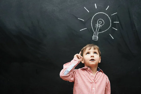 Hes got a lot of ideas. Studio shot of a young boy with a chalk-drawing light bulb above his head. — Stock Photo, Image