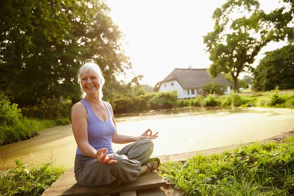 Jag njuter bara av skönheten omkring henne. Skjuten av en attraktiv mogen kvinna mediterar i en trädgård vid solnedgången. — Stockfoto