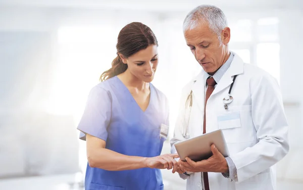 Comparando registros médicos. Fotografía de dos profesionales médicos mirando una tableta digital. — Foto de Stock