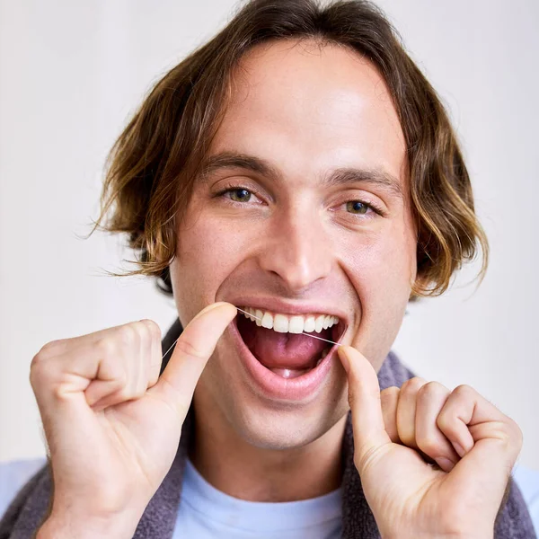 Assicurati di metterti tra quei denti. Colpo di un giovane uomo filo interdentale i denti. — Foto Stock