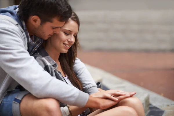 Compartir un momento íntimo. Una feliz pareja joven sentada afuera teniendo un momento íntimo. —  Fotos de Stock