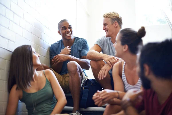 Він знає, як змусити групу сміятися. Обрізаний знімок студентів університету, які розмовляють, сидячи на сходах . — стокове фото