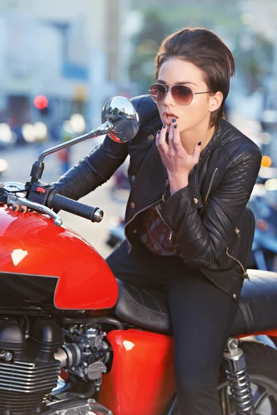 Se ve bien.... Una hermosa joven motociclista mirándose en su espejo de bicicletas. — Foto de Stock